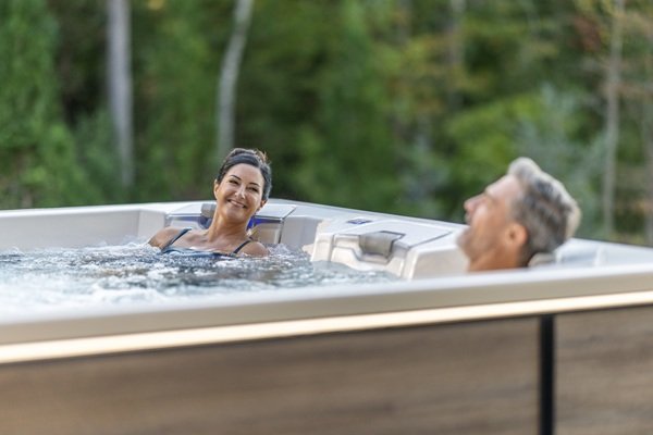 A man and a woman relaxing in a hot tub outside.