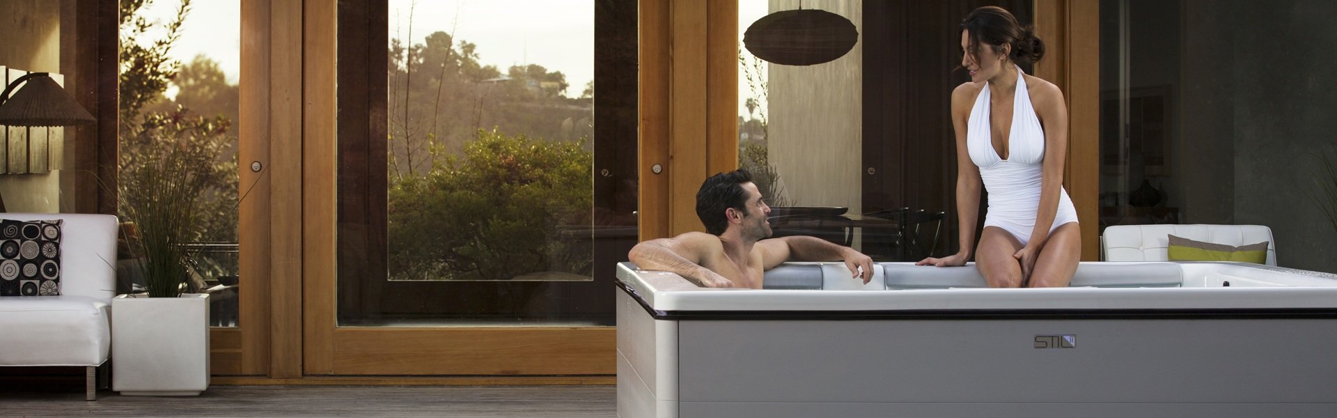 Two people sitting in a hot tub on their back patio.