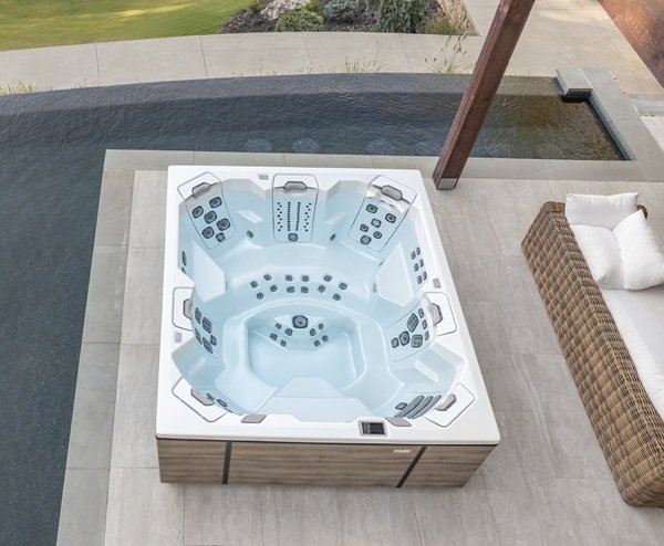 A birds-eye view of a Bullfrog Spa sitting on a patio surrounded by a pool. You can see the inside of the spa and the seating layout.