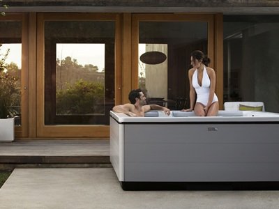 Two people sitting in a hot tub on their back patio.