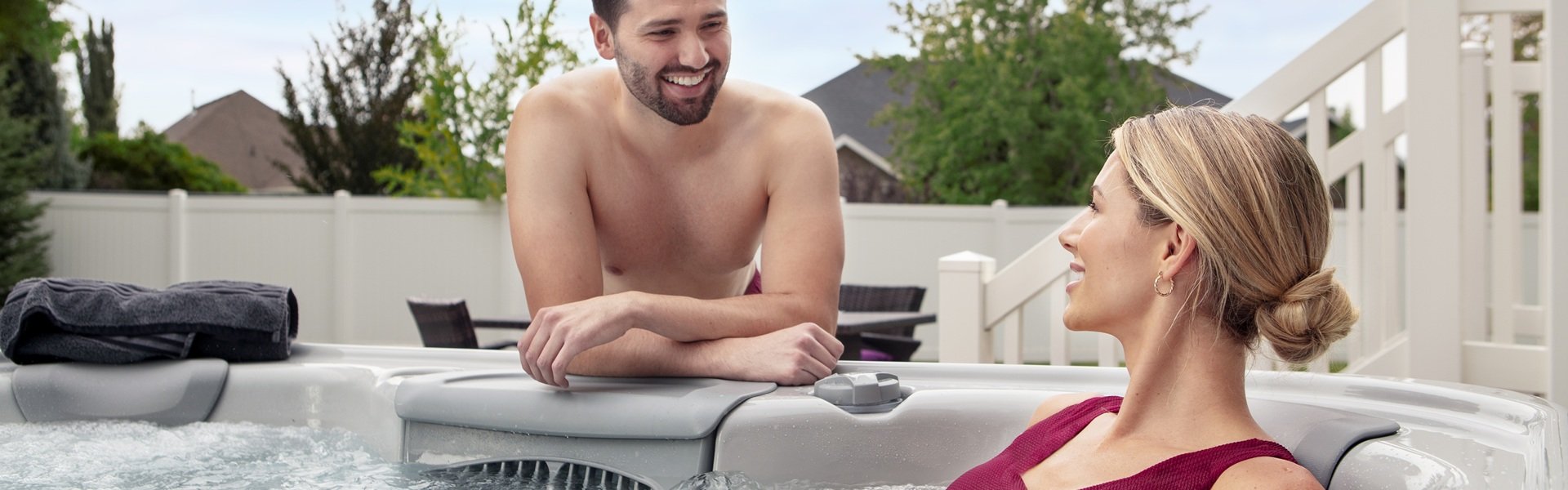 A man sitting outside of a hot tub and a woman sitting in the hot tub and they are having a conversation.